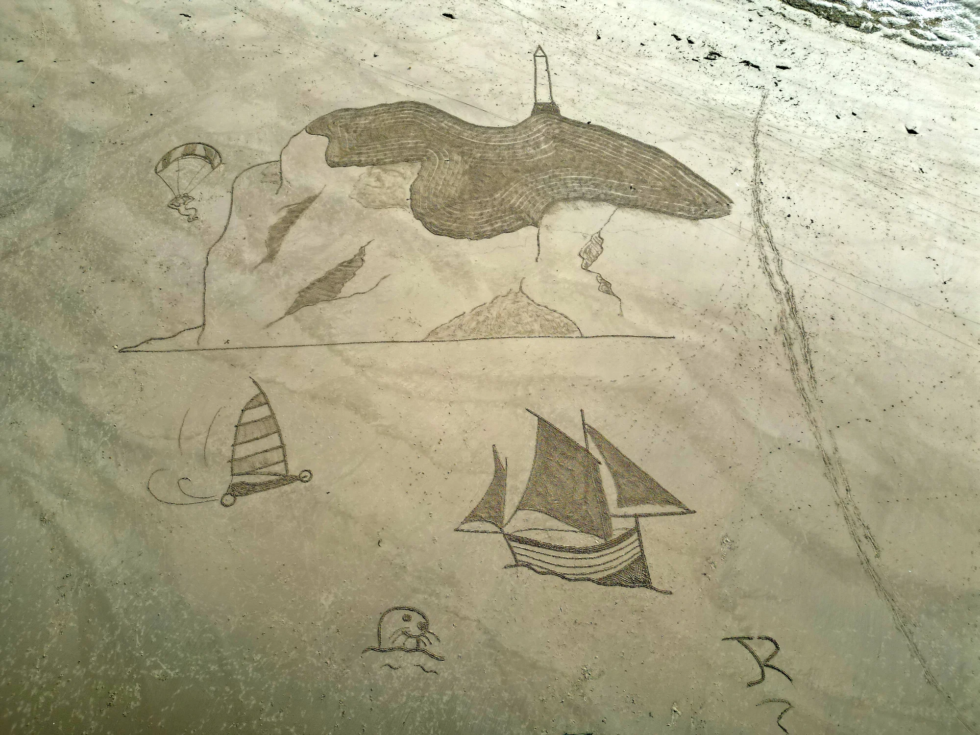 Grande fresque maritime composée d’un phare, de voiliers et d’animaux tracés dans le sable