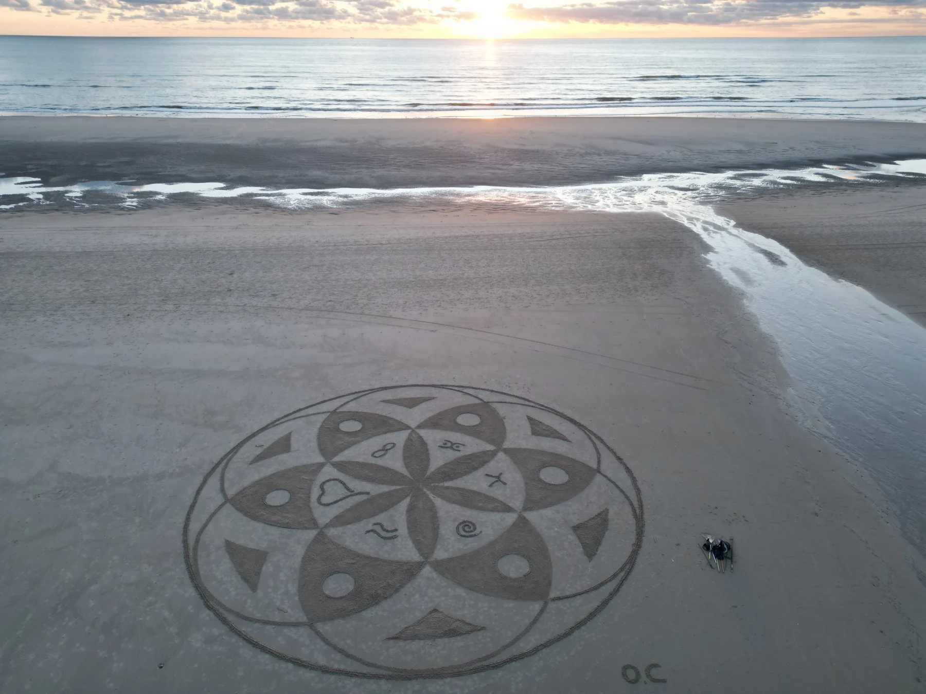 Mandala de sable face à la mer sous la lumière d’un coucher de soleil