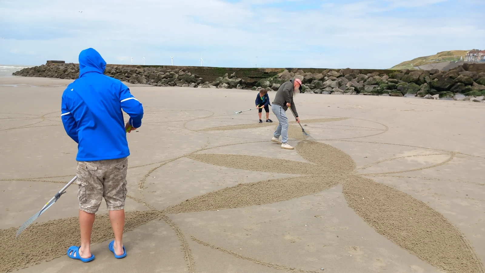 Participants traçant et remplissant les premières formes d’un mandala dans le sable