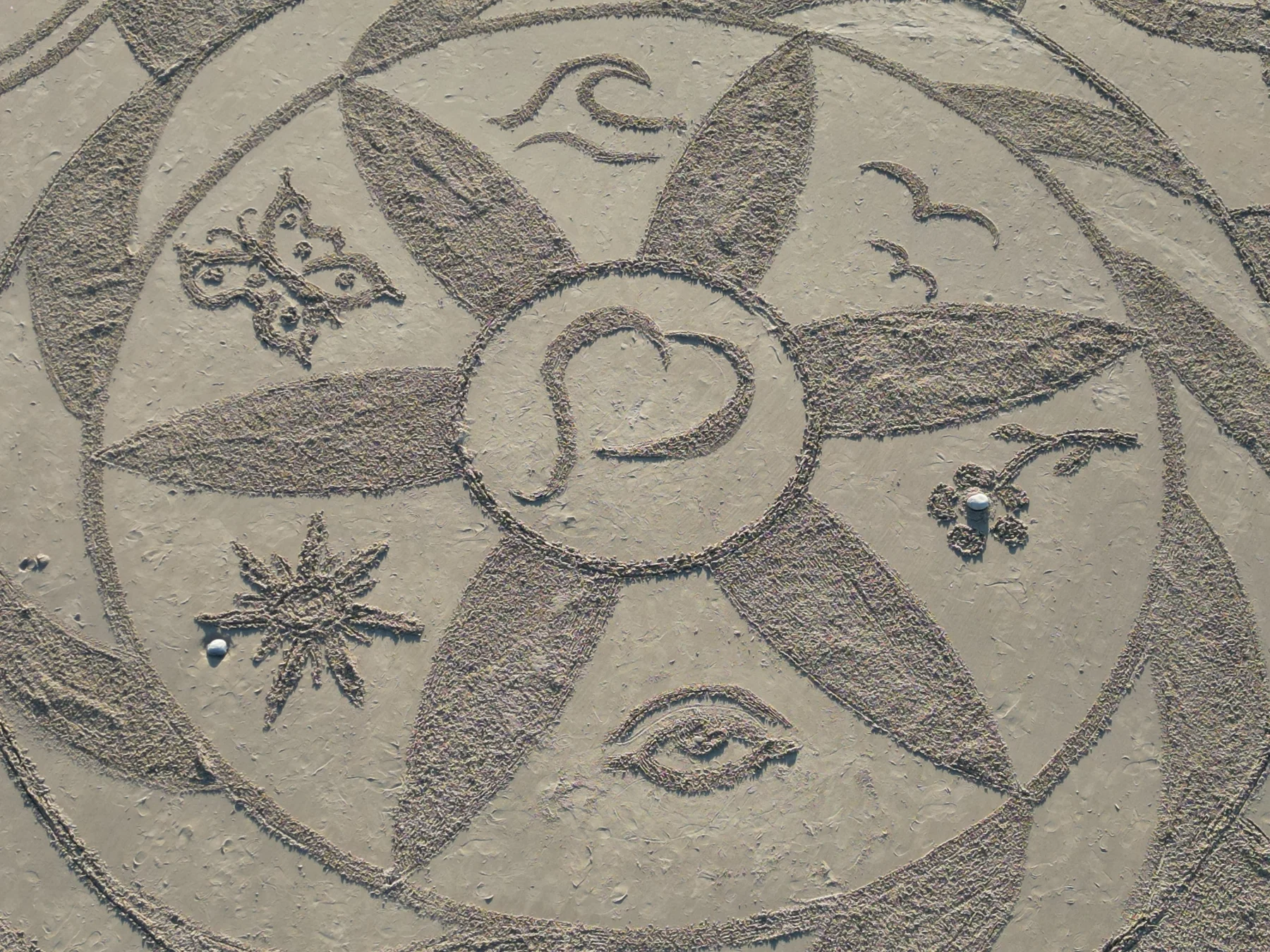 Mandala de sable mêlant formes circulaires, motifs naturels et symboles