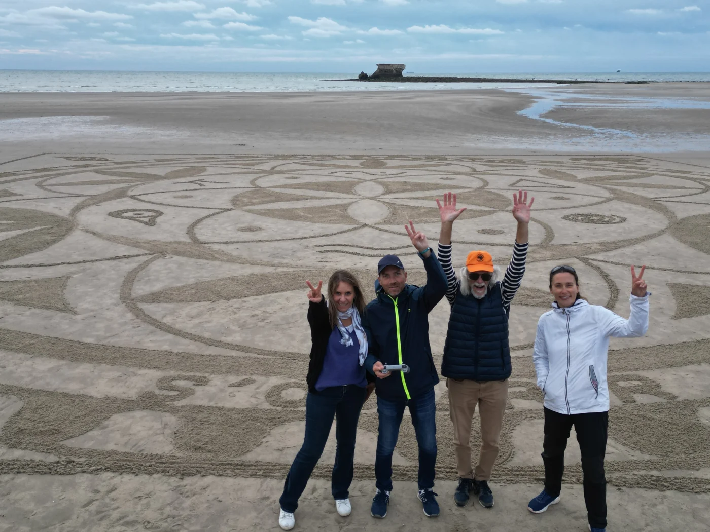 Groupe de participants devant une grande création collective sur la plage