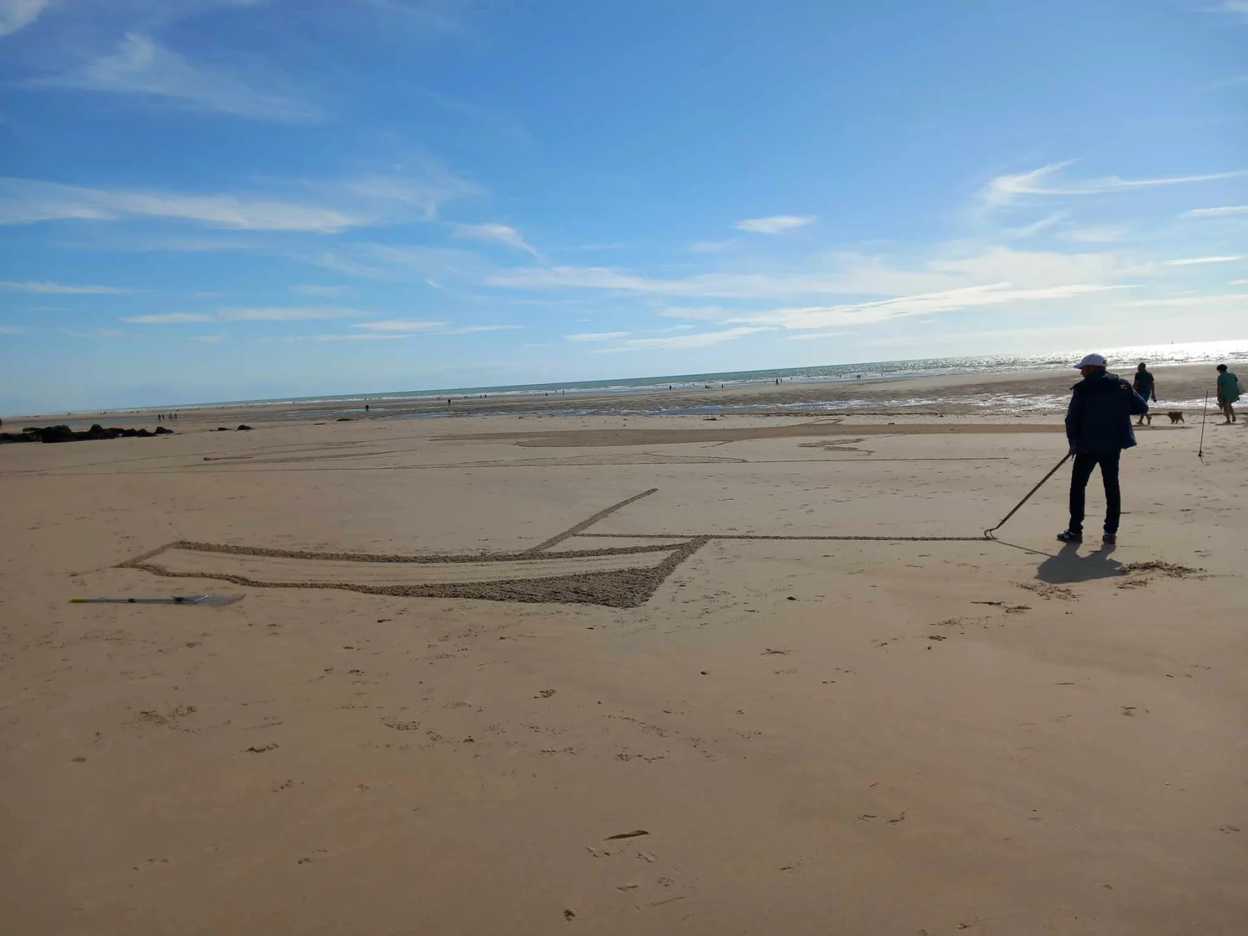Personne traçant une grande forme dans le sable à l’aide d’un outil