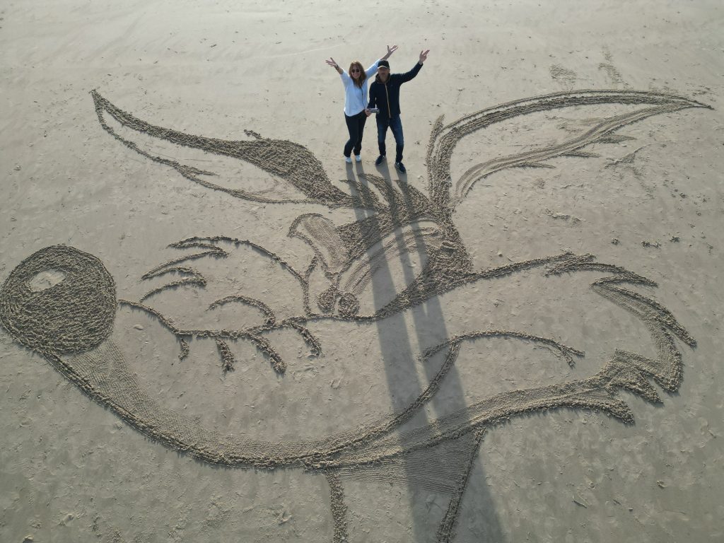 Vue rapprochée de la tête de Coyote dessinée dans le sable, avec deux personnes au-dessus du tracé