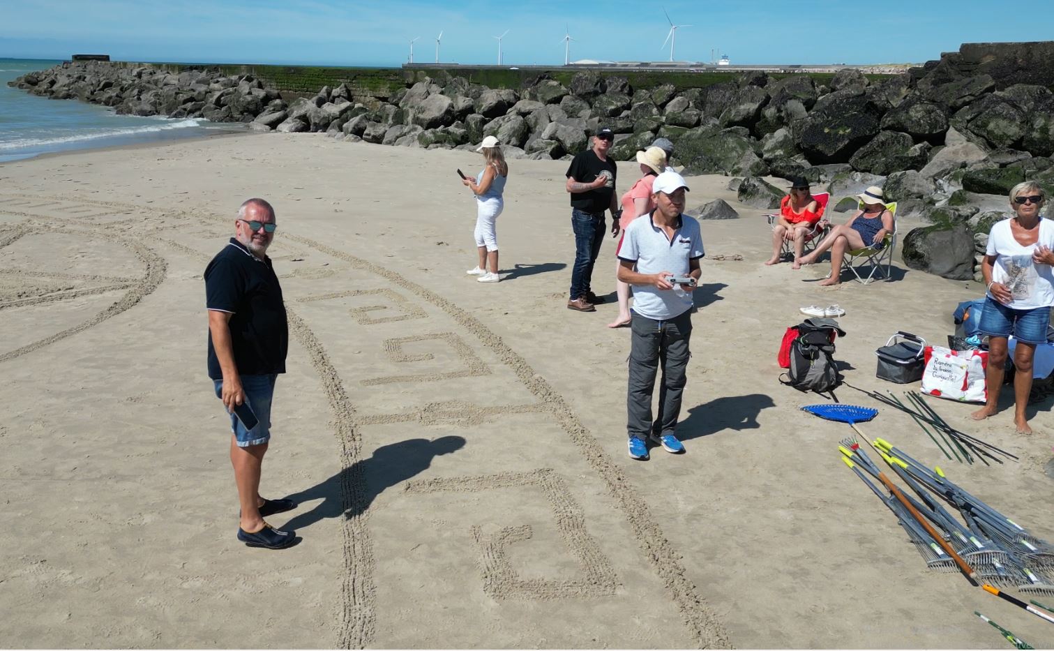Participants et matériel de traçage autour d’une création en cours sur la plage