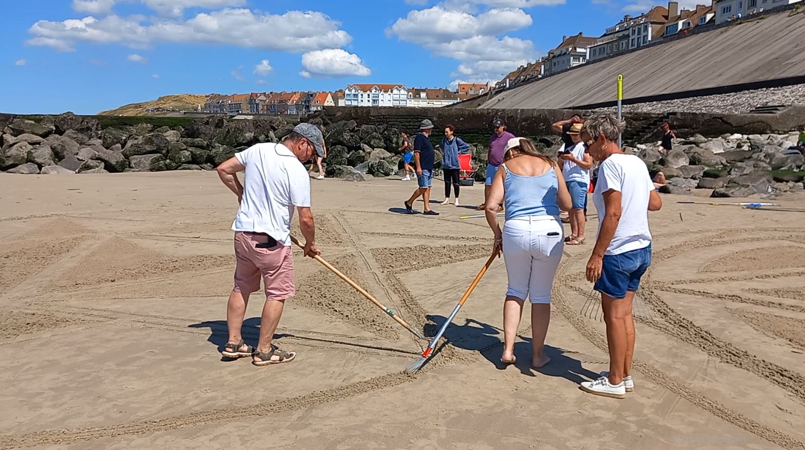 Participants traçant collectivement une création dans le sable au Portel